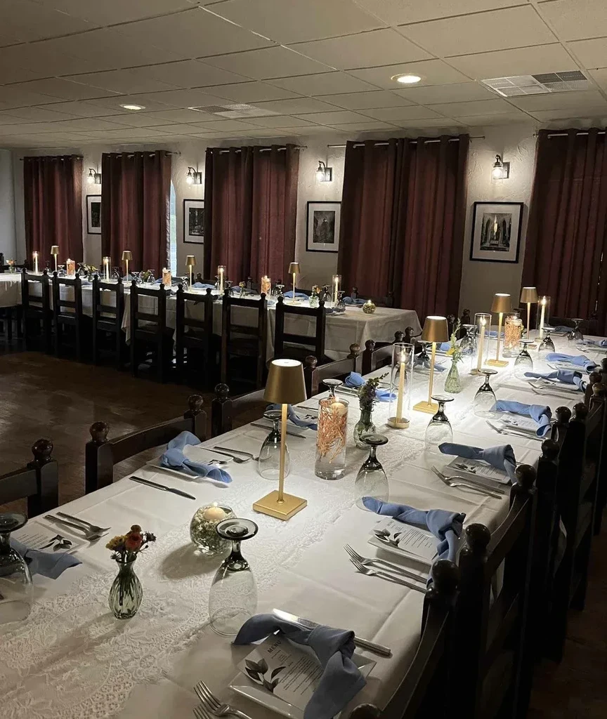 Formal dining room with long tables, elegant place settings, and warm lighting.