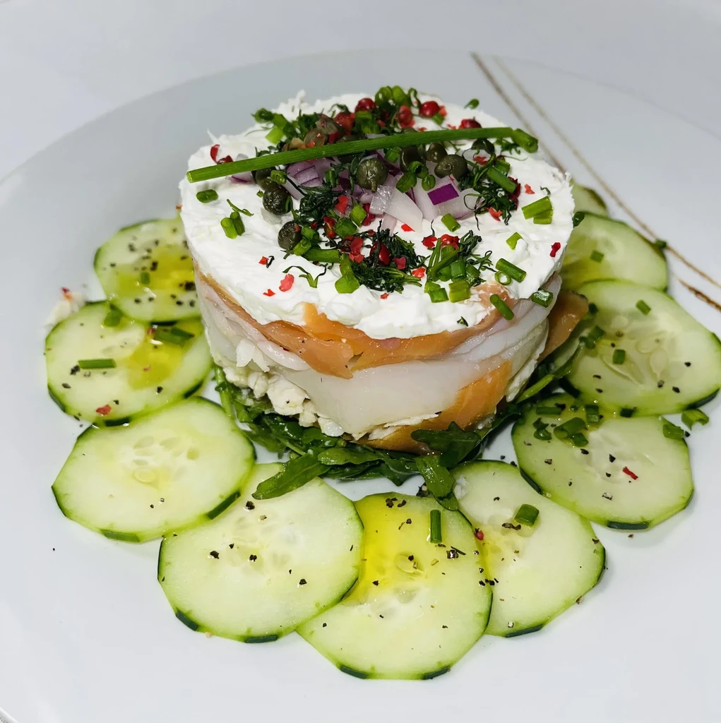 Layered salmon and cream cheese terrine with cucumber and garnishes.