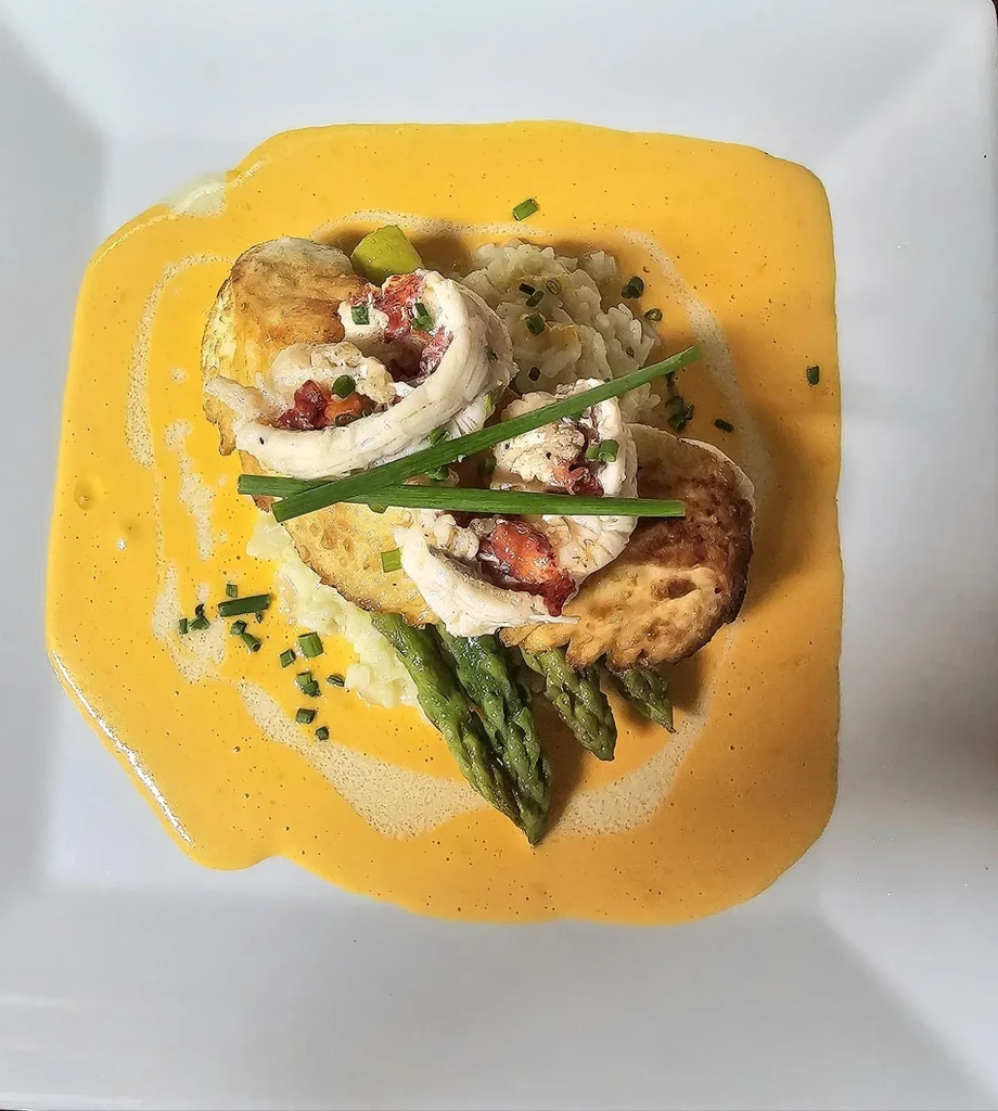 Meticulously plated rolled fish, asparagus, rice, and orange sauce.