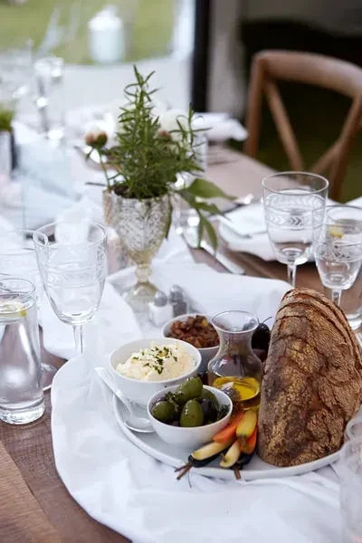 A table set with bread, olives, dips, and wine glasses.