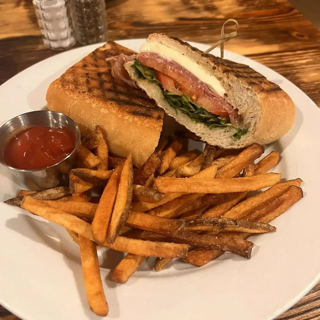 Cut grilled sandwich revealing fillings, with french fries and ketchup.