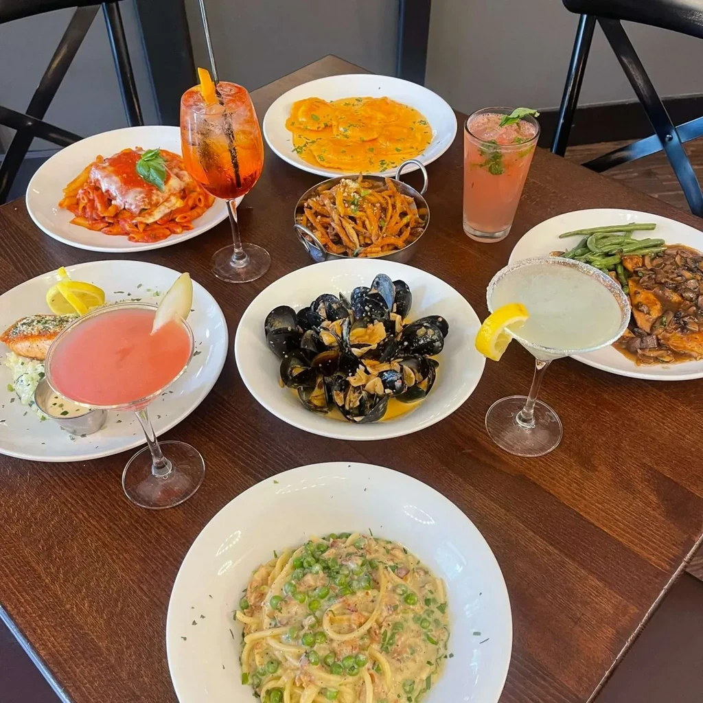 Overhead: dark table with various Italian dishes and colorful cocktails.