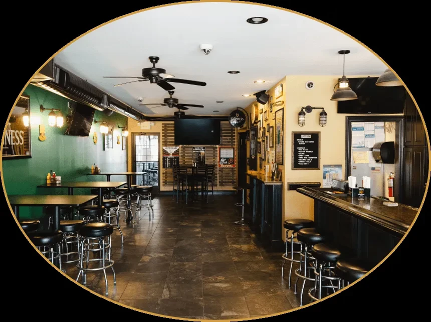 Empty pub interior with dark bar, high-top tables, and Guinness decor.