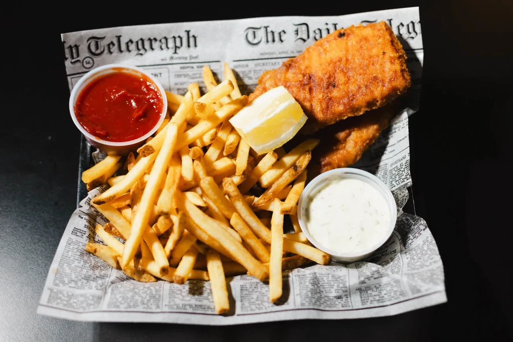 Golden fish and chips with lemon, ketchup, and tartar sauce.
