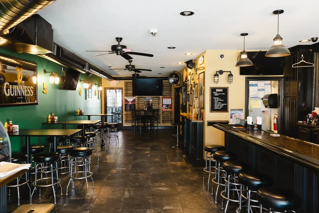 Empty pub interior with dark wood bar and Guinness mirror.