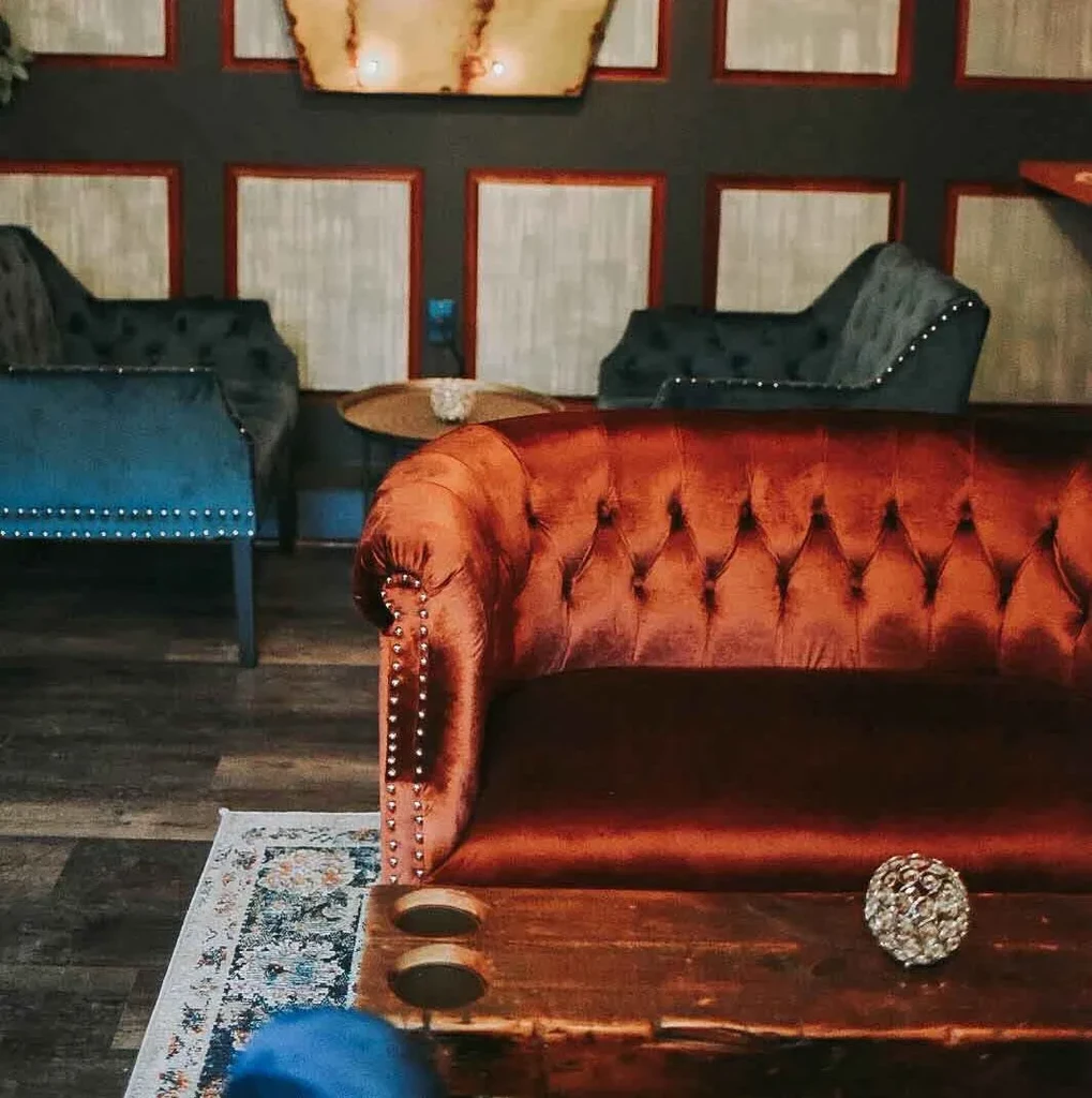 Elegant restaurant lounge with orange velvet sofa and dark, atmospheric lighting.
