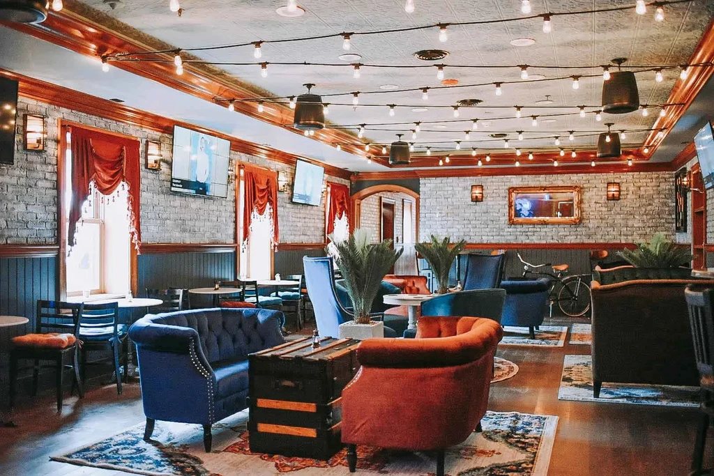 Warm, sophisticated bar interior with brick, plush seating, Edison bulbs.