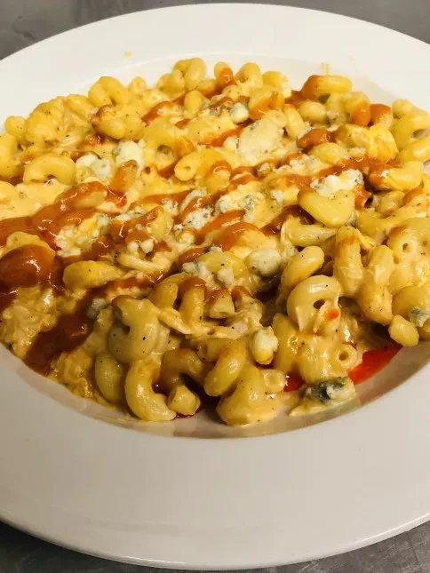 Elbow macaroni and cheese with cheese crumbles and spicy red sauce.