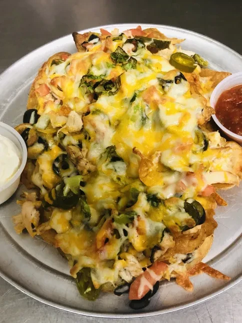 Loaded nachos with chicken, cheese, vegetables, sour cream, and salsa.
