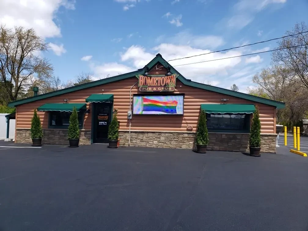 Rustic Hometown Pub & Grub building with a prominent rainbow flag display.