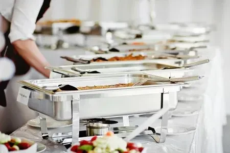 Well-lit buffet line with hot food, fresh salads, and a server.