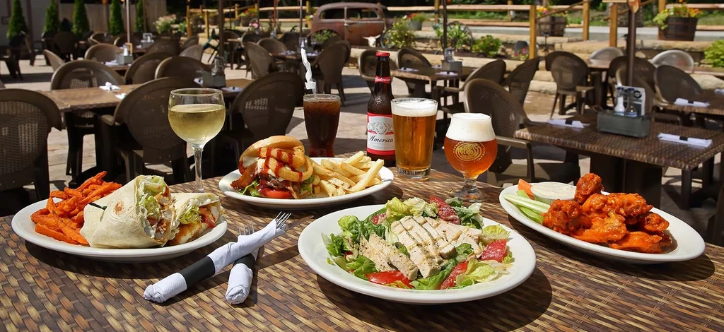 Outdoor dining table with various plates of food and drinks.