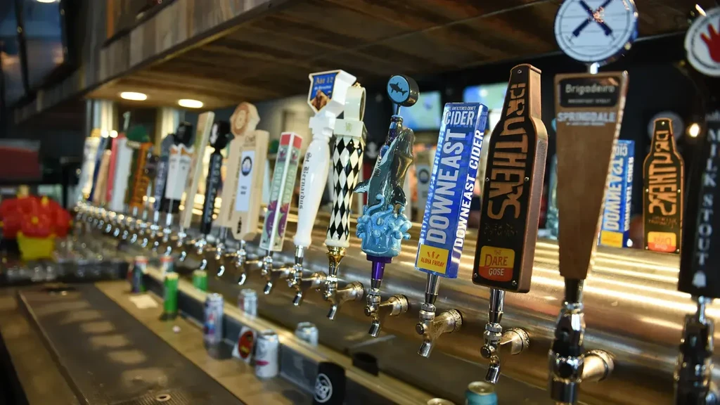 A long row of unique, polished beer and cider tap handles.