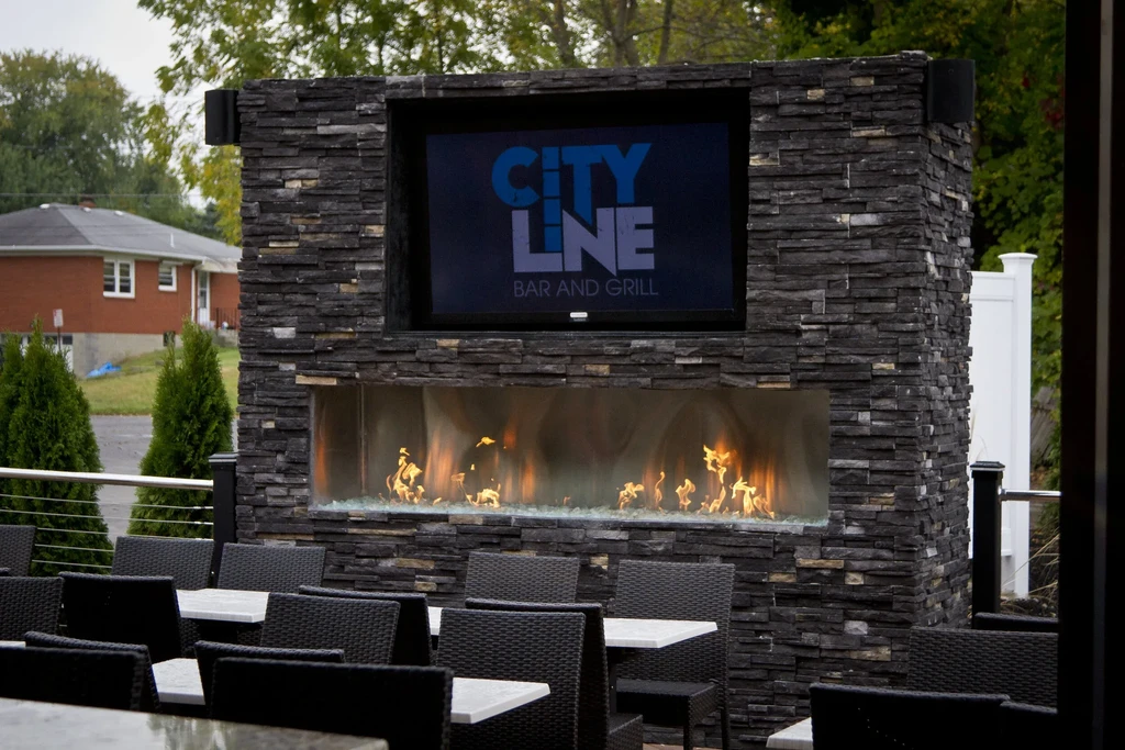 Empty City Line Bar and Grill patio with stone fireplace and TV.