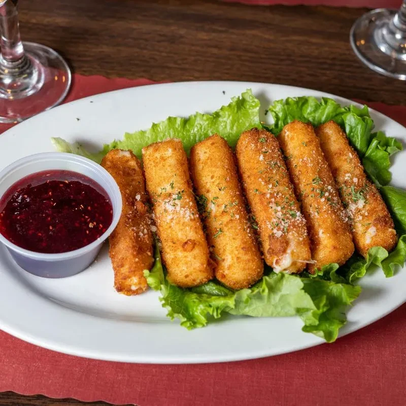 Fried cheese sticks on lettuce with a red dipping sauce.