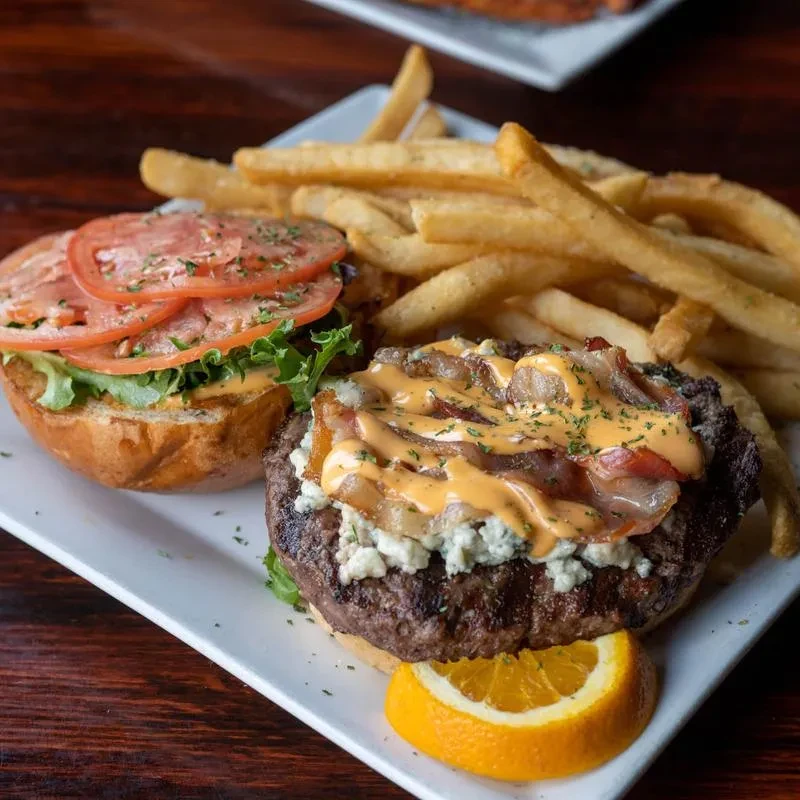 Deconstructed gourmet burger with blue cheese, bacon, fries on a plate.