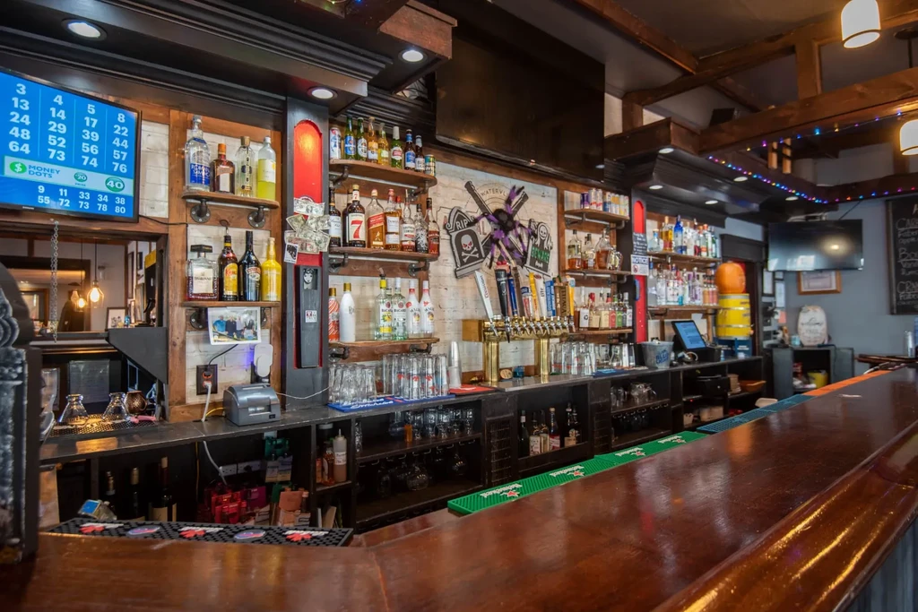 Well-stocked bar interior with a long wooden counter and Halloween decor.