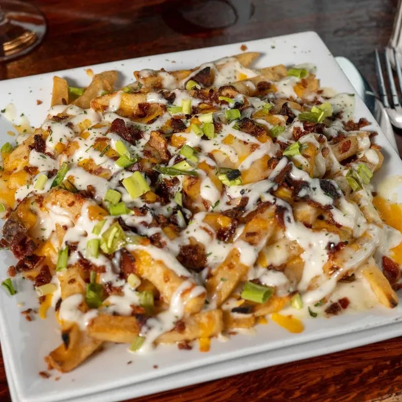 Loaded fries with melted cheese, crispy bacon, sauce, green onions.