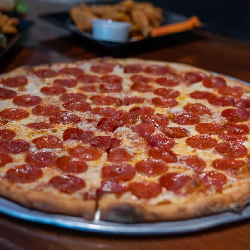 Large, freshly baked pepperoni pizza on a pan with melted cheese.