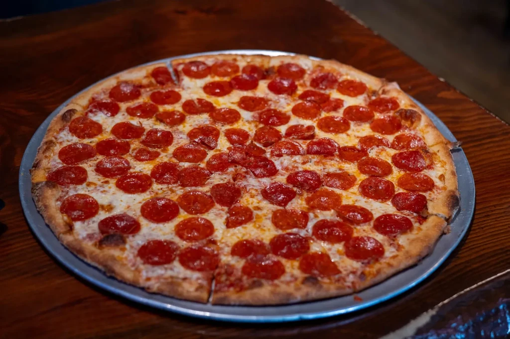 Pre-cut pepperoni pizza with melted cheese on a silver pan.