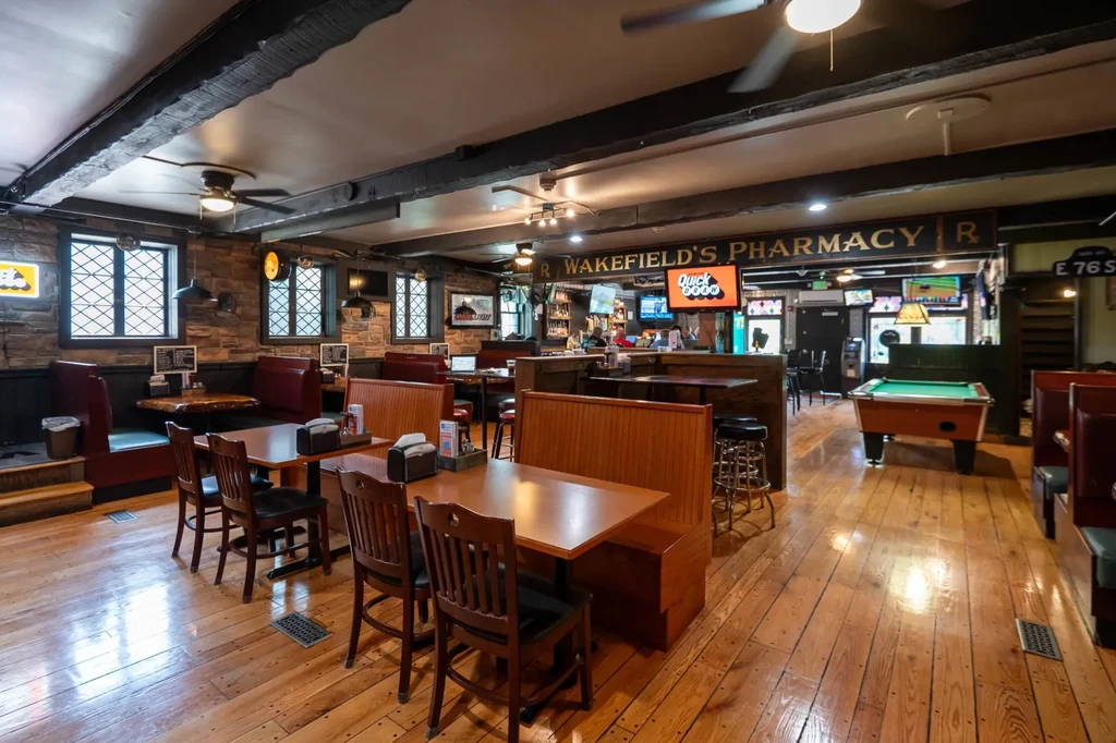 Interior of a rustic pub with bar, seating, and a pool table.
