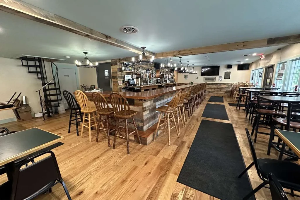 Empty rustic restaurant with an L-shaped bar and dining area.