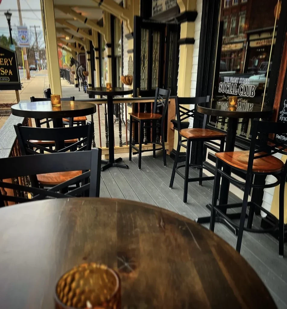 Front Street Social Club patio with dark wood tables, chairs, candles.