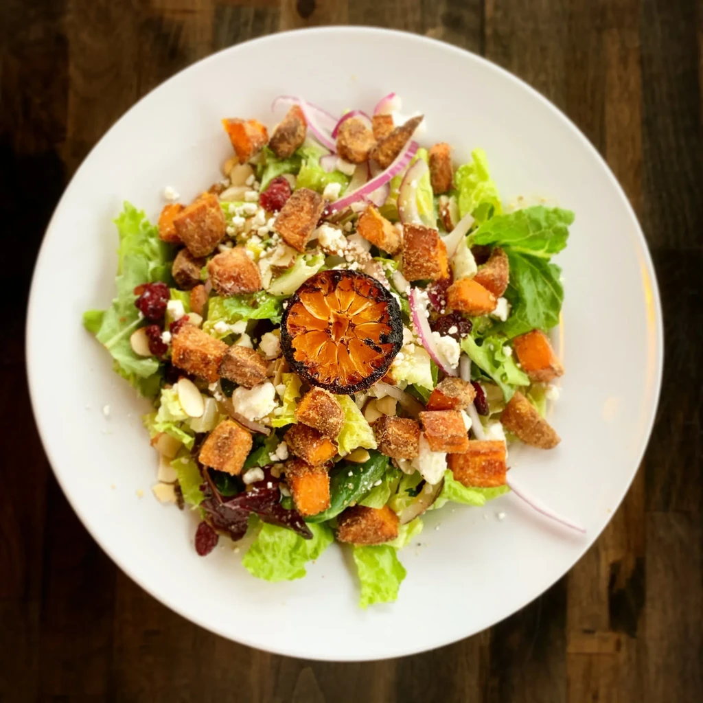 Colorful salad with roasted vegetables, cranberries, cheese, and charred citrus.