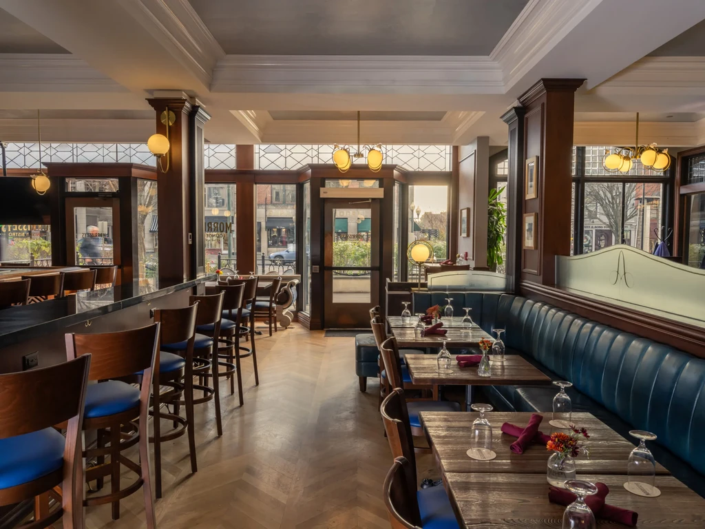 Well-appointed restaurant interior with dark wood, blue booths, and bar.