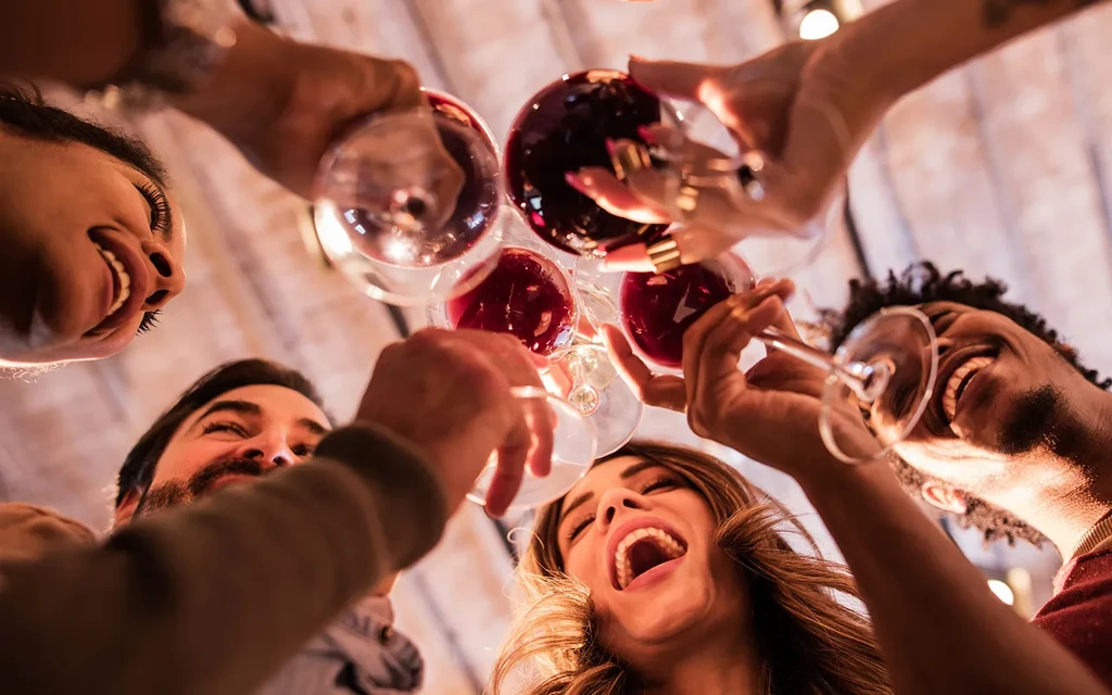 Joyful group of people clinking red wine glasses together, smiling.