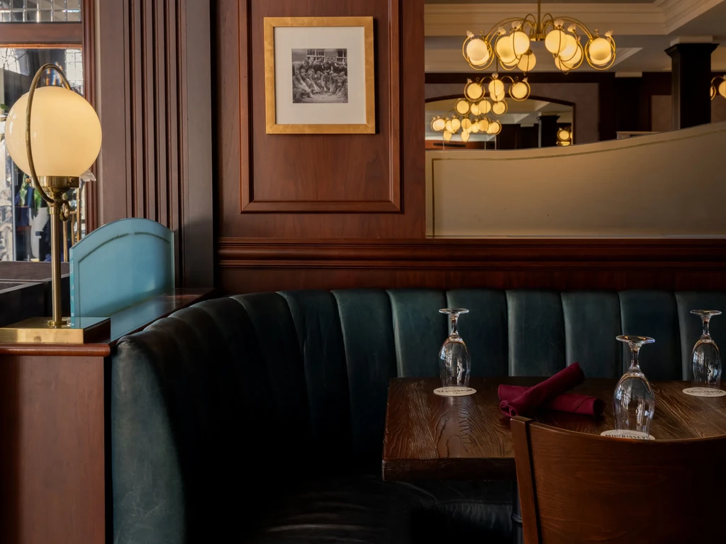 Cozy restaurant interior with tufted booth, brass lamp, and framed art.
