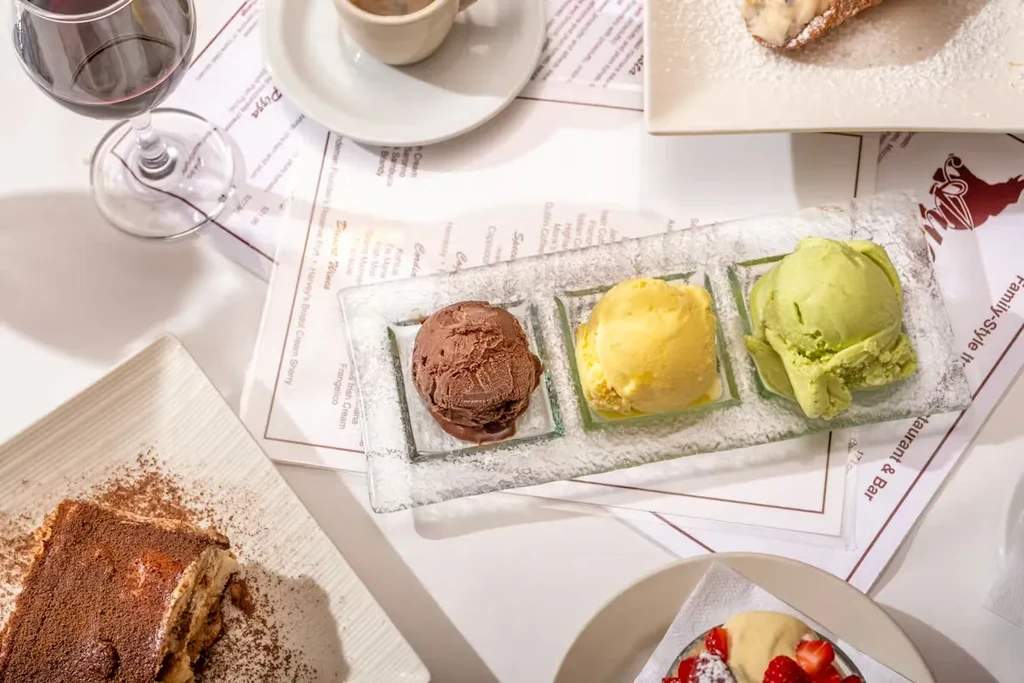 Dining table overhead with desserts, ice cream, wine, and coffee.