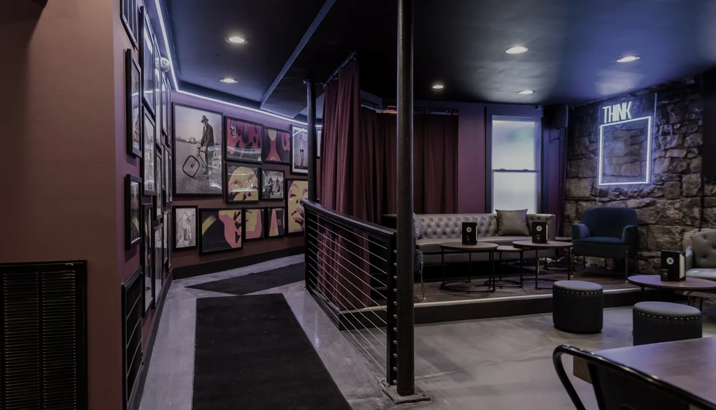 Moody restaurant lounge with gallery wall and 'THINK' neon sign.