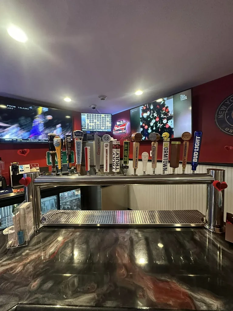 Stainless steel draft beer taps at a red bar with multiple TVs.