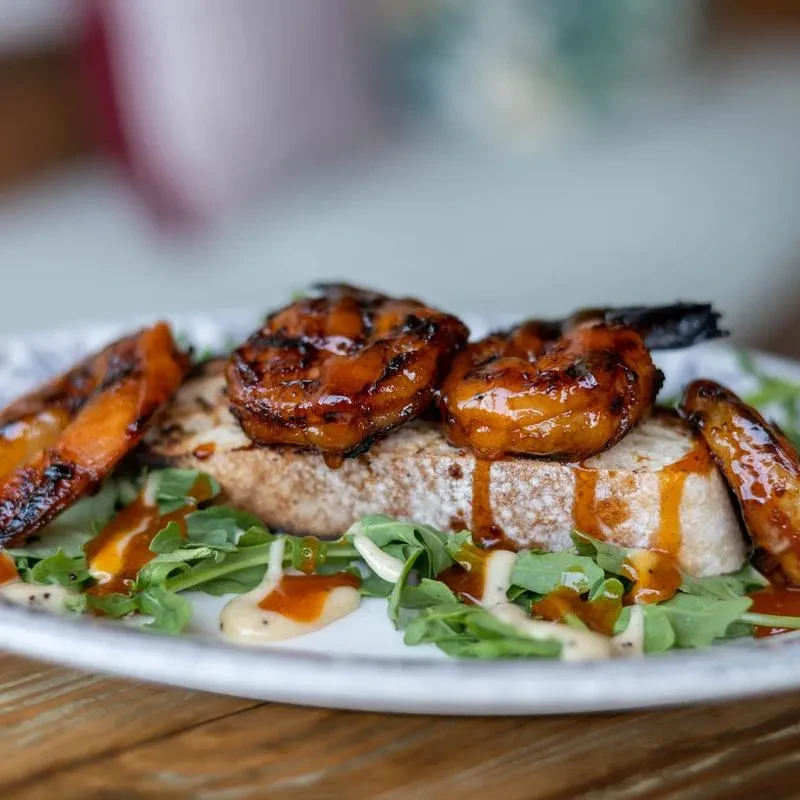 Glazed grilled shrimp and peaches on rustic bread, arugula.
