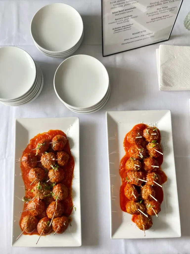 Overhead view of mini beef meatballs on platters with menu and plates.