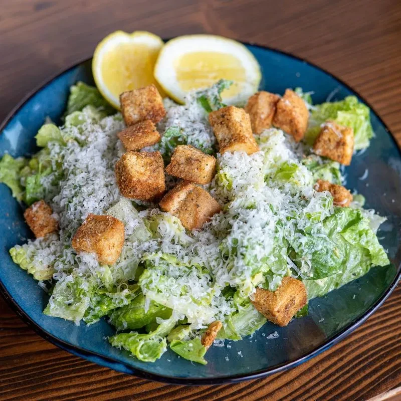 Close-up of Caesar salad with romaine, Parmesan, croutons, and lemon.