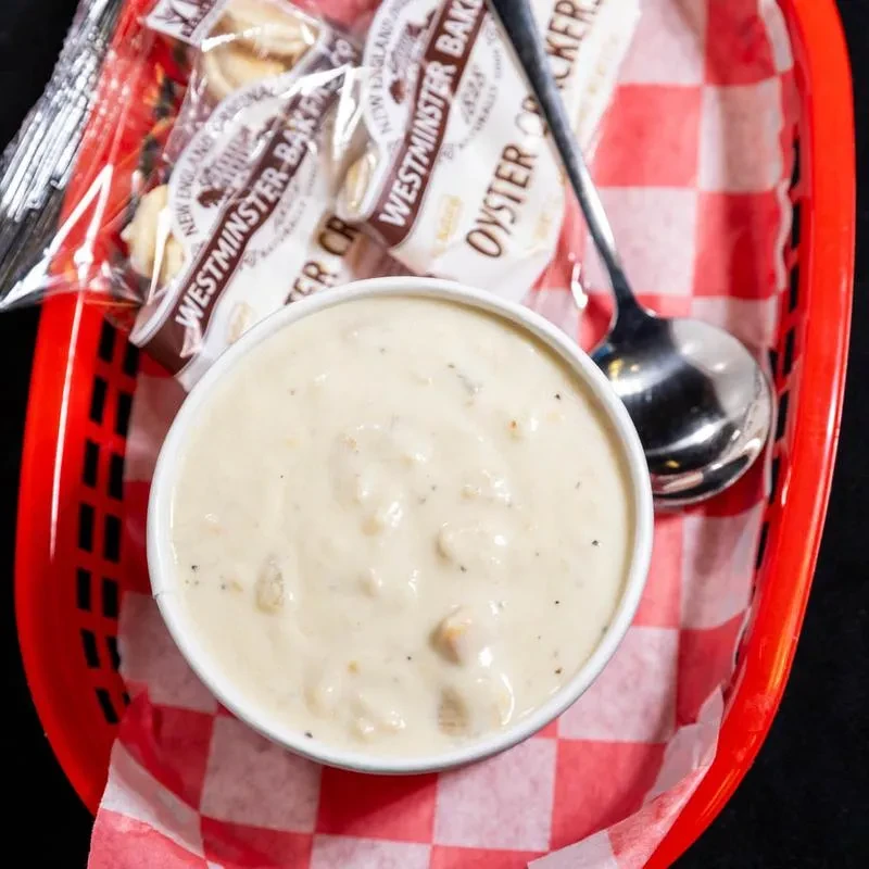 Top-down view of creamy chowder with oyster crackers in red basket.