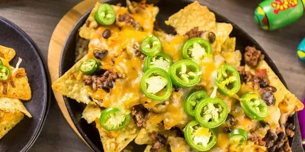 Loaded nachos in a skillet with cheese, beans, and jalapeños.