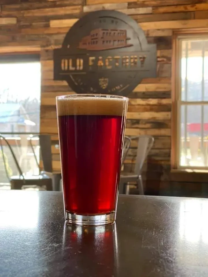 Beer glass on bar top, "OLD FACTORY" sign on rustic wall.