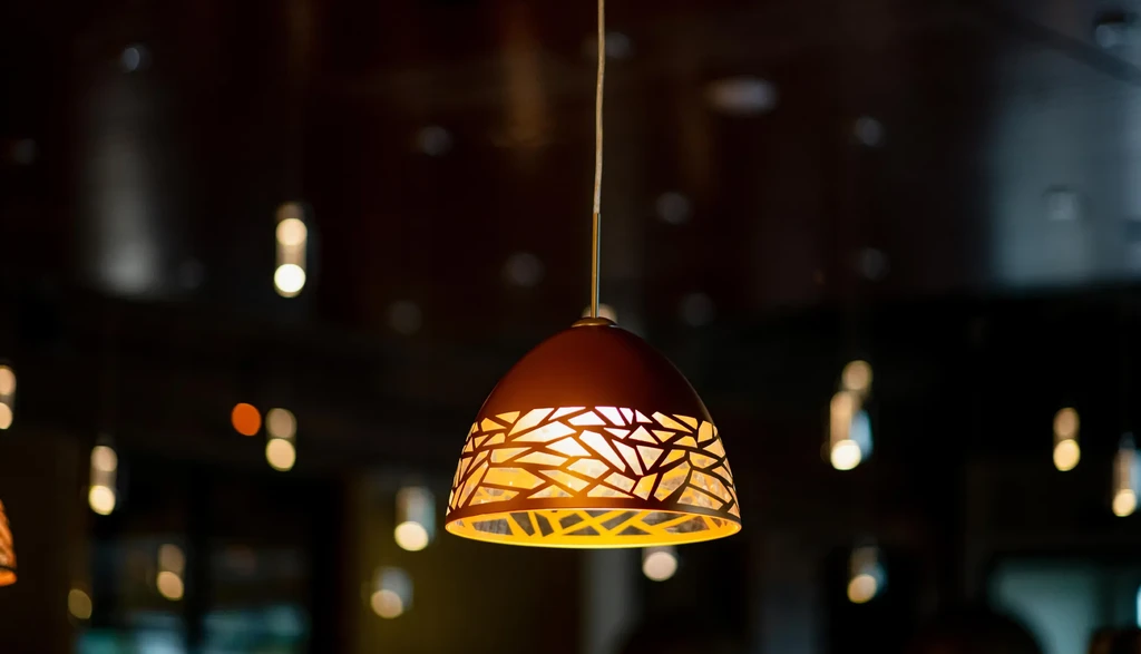 Geometric pendant light casts warm glow on blurred, dark background.