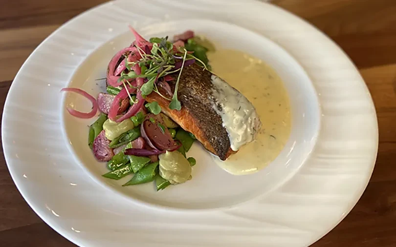 Seared fish, crispy skin, colorful vegetables, microgreens, and creamy sauces.