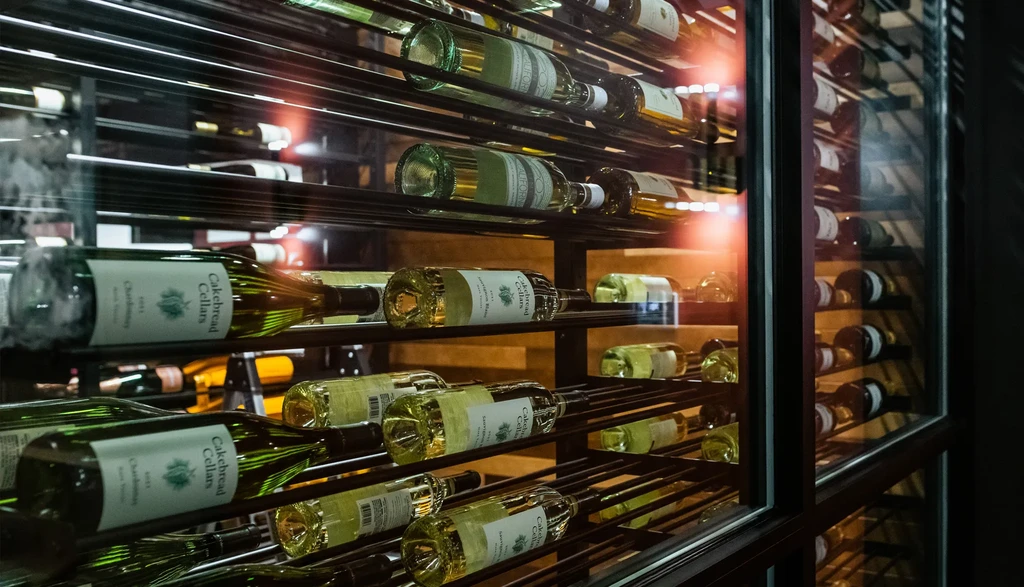 Glass door view of a wine cellar stocked with white wines.