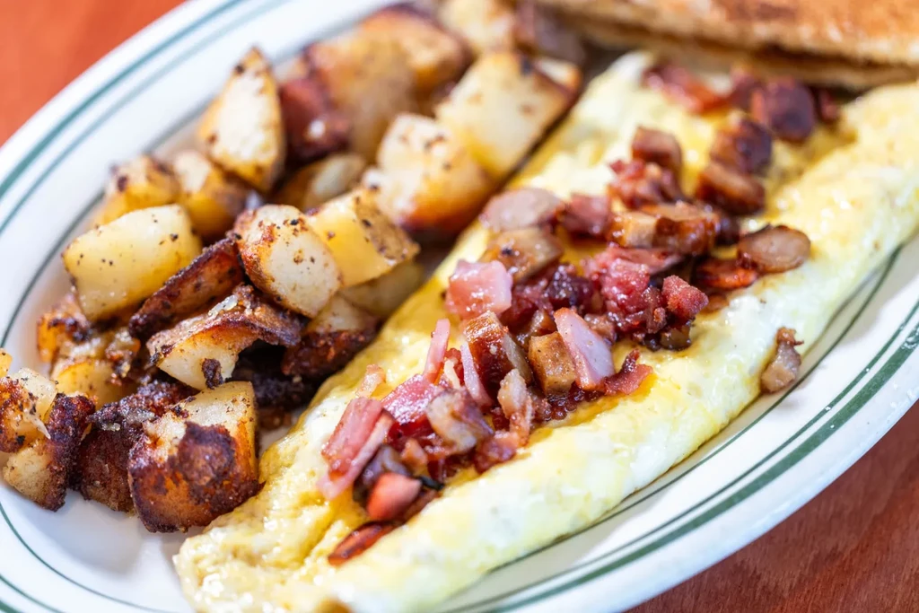 Breakfast plate with bacon omelet, golden home fries, and toast.