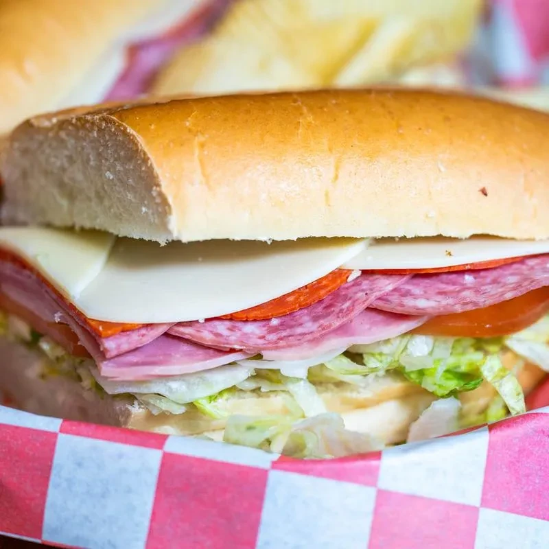 Sub sandwich filled with deli meats, cheese, lettuce, and tomato.