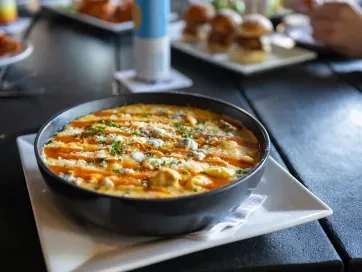 Dark bowl of macaroni and cheese with blue cheese, herbs, hot sauce.