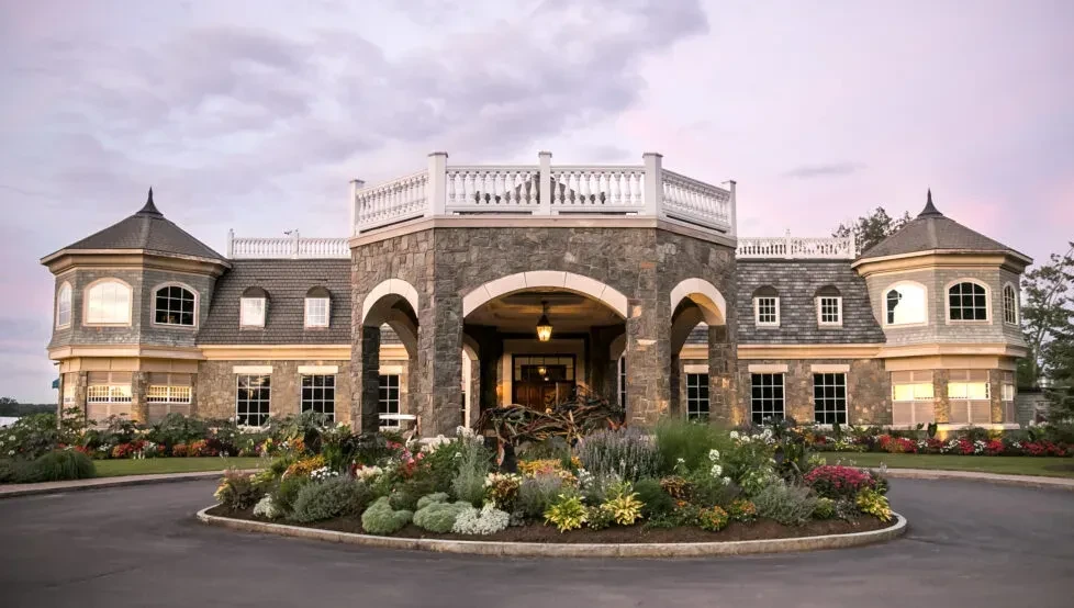 Elegant stone building with prominent portico, turrets, and landscaped garden.