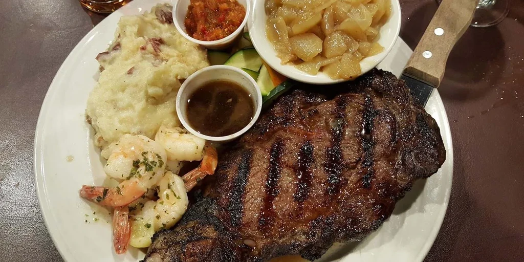 Overhead view: grilled steak, mashed potatoes, shrimp, sauces, and vegetables.
