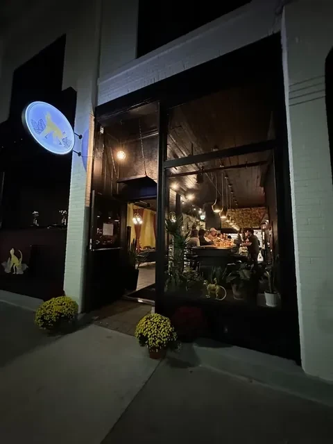 Restaurant exterior at night, glowing animal sign, people visible inside.