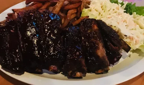 Plate of glistening BBQ ribs, creamy coleslaw, and golden fries.